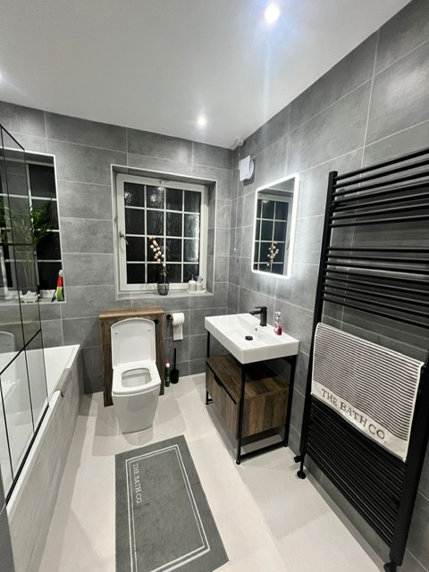 Modern grey tiled bathroom with black framed shower screen
